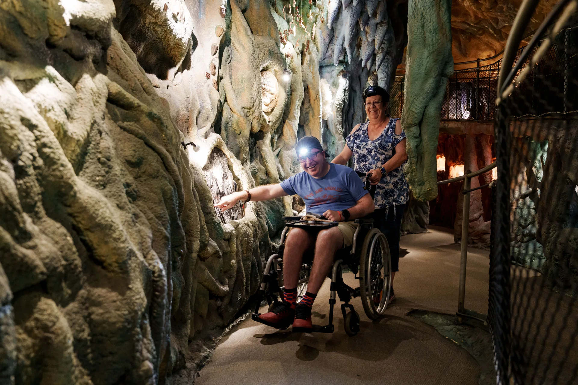 A visitor in a wheelchair explores the wheelchair-accessible cave passages with a companion at Crystal Caves